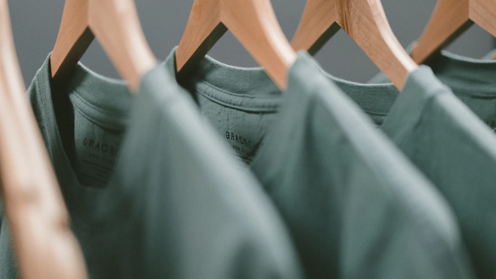 Sage hand-dyed tees on wooden hangers